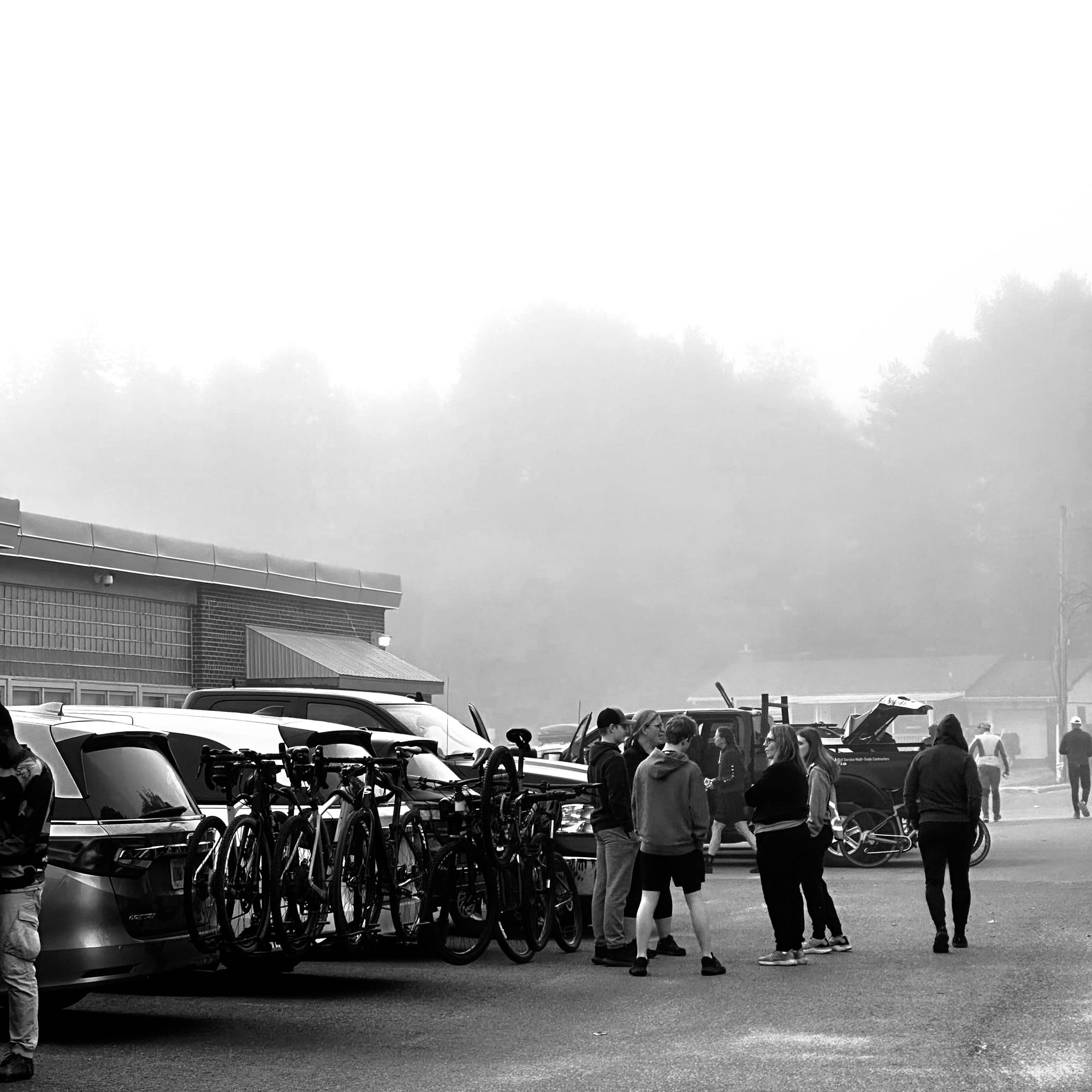 Black and White photo of people chatting near their bike rack full of bikes